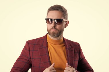 İş ceketli ve güneş gözlüklü bir adam. Olgun adam erkek giyim tarzı giyinir. Şık ve modaya uygun. İspanyol manken. Beyaz giysili şık erkek kıyafetleri. Gösterişli moda belirleyici.