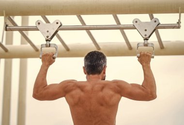 Spor eğitimi. Sporcu adam egzersiz yapıyor. Adam kaslı sırt sporcusu açık hava spor salonunda barfiks çekiyor. Kas kasları ve trisepsler. Güçlü bir atlet. Adam yanaşıyor. Spor barfiks egzersizi.