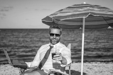 Denizde serbest çalışan bir adam. Yazın iş adamı. Çevrimiçi serbest çalışma. Dizüstü bilgisayarı olan bir işadamı. Kumsalda dizüstü bilgisayar kullanan bir iş adamı. Seyahat ve iş. İşlem sırasında ağ kuruluyor.