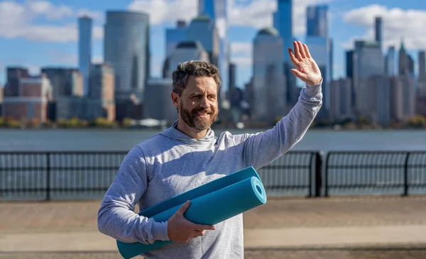 Sporcu adam antrenmana hazır. Sağlıklı bir yaşam tarzı. Spor ve spor. Eğitim için yoga minderi. New York 'ta sporcu. Manhattan 'da spor kıyafetli bir adam. Vücuduna uygun. Yoga hocası selam söyledi..