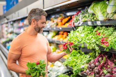 Sağlıklı bir yaşam tarzı. Taze gıda mağazası. Marketteki adam. Sebze süpermarketinden alışveriş yapan bir adam. Turplu market tüketicisi. Markette turp satan bir adam. Baharatlı turp..
