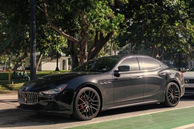 Miami, Florida, ABD - 17 Aralık 2024: Black 2014 Maserati Ghibli spor yara izi. Maserati Ghibli 'nin lüks spor arabası. Maserati Ghibli 'nin arabası dışarıda park edilmiş. Siyah Maserati Ghibli, köşe görünümü.