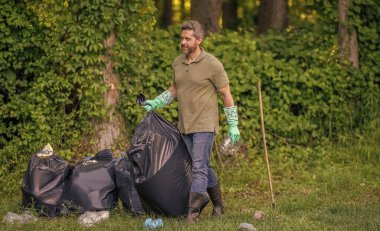Çevresel koruma. Çevreci adam. Çevresel koruma. Çevreyi koru. Çevre plastik kirliliği. Gönüllü adam ormanda çöp topluyor. Boşluğu kopyala.
