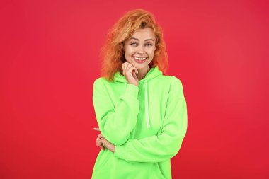 Kapüşonlu kadın model. Çekici bir kadının şık bir görünüşü var. Kız havalı görünüyor. Minimum giysi. Kızıl saçlı mutlu kadın pembe üzerine izole edilmiş günlük giysiler giyiyor. Yaşam tarzı kavramı.