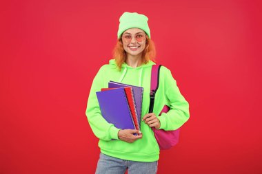 Kız öğrenci çalışma kitabını tutuyor. Okula dönelim. Bilgi toplama günü. Üniversitede eğitim. Pembe üzerine izole edilmiş bir kızın ödevi. Bilgi ve eğitim. Okul eğitimi. Modern eğitim. Bilgi güçtür..