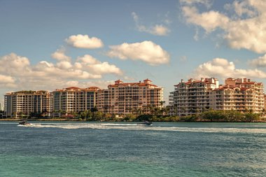Marinaya yüzen bir tekne. Fisher Adası 'nda lüks bir yat teknesi. Yaz tatili. Fisher Adası konut binası ve lüks yat teknesi. Miami 'de Fisher Adası' na yat gezisi..