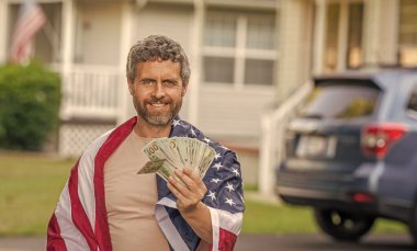 Vatansever adam. Amerikan bayrağı ve dolar parası olan adam. Enflasyon konsepti. Amerikan vergi politikası. İspanyol adam ve Amerikan bayrağı. Amerika 'da vergi ödemek. Katma değer vergisi. Vergilendirme sistemi pankartı.