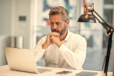 Ofiste dizüstü bilgisayar kullanan bir adam. Serbest iş yapma. Erkek ofis yöneticisi. İş adamının internet işi var. İş adamı başarısı. Serbest çalışan adam internette çalışıyor. Çevrimiçi çalışan serbest çalışan. Ofis çalışanı.