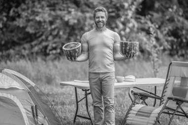 Kamp ve doğa pikniği. Adam kampı. Karpuz kampı pikniği. Lezzetli sağlıklı yiyecekler. Kampta taze yiyecek. Yaz kampında karpuzlu bir adam. Yaz günü doğa yürüyüşçüsü. Mutlu yaz..