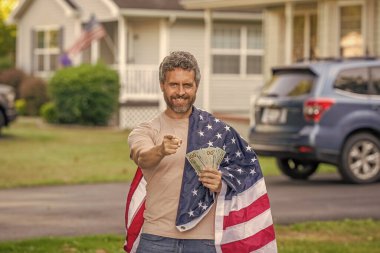 İspanyol adam ve Amerikan bayrağı. Amerika 'da vergi ödemek. Katma değer vergisi. Vergi sistemi. Vatansever adam işaret ediyor. Amerikan bayrağı ve dolar parası olan adam. Enflasyon konsepti. Amerikan vergi politikası.