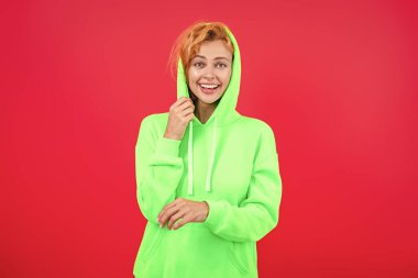 Pembe kapüşonlu bir kadın. Moda modeli. Şık kapüşonlu kızıl saçlı kız. Sıradan kapüşonlu, şık, beyaz bir kadın. Modayla ilgilenen kız modaya uygun ve parlak görünüyor. Rahat ve şık..