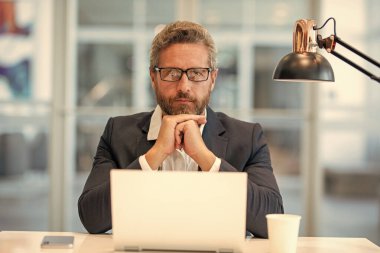 Çevrimiçi çalışan serbest çalışan. Ofiste dizüstü bilgisayar kullanan ciddi bir adam. Serbest iş yapma. Erkek ofis yöneticisi. İş adamının internet işi var. İş adamı başarısı. Serbest çalışan adam internette çalışıyor..