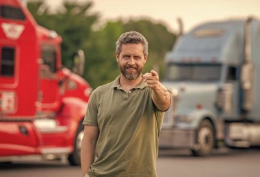 Kamyonun önünde yakışıklı bir şoför. Kamyon sahibi. Kamyon şoförü. Kamyon kamyonunun yanında bir erkek kamyon şoförü. Nakliye araçları. Yarı kamyon aracı. İspanyol kamyoncu, işaret parmağı..