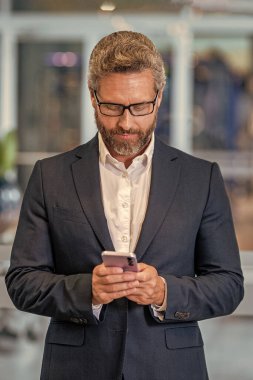 Telefon kullanan bir iş adamı. Takım elbiseli adam telefonu sohbeti. Telefonu olan olgun bir İspanyol iş adamı. İş iletişimi. Mesajlaşma ve mesajlaşma. İş adamı ofiste telefonda konuşuyor..