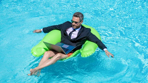 Uzaktan kumanda çalışıyor. Yaz tatili. Komik çılgın iş adamı resmi olarak havuzda dinleniyor. Çılgın yaz. Eğlenceli iş hayatı. Yüzme havuzunda dizüstü bilgisayarı olan iş adamı..