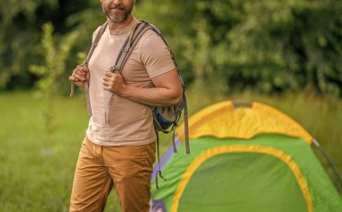 Yaz kampındaki adam. Kamp macerası. Yürüyüş konsepti. Kamp çadırı. Kampta çadır kurmuş, manzarası kesilmiş bir adam var. Yaz günü doğa yürüyüşçüsü. Yaz kampı ve doğa tatili.