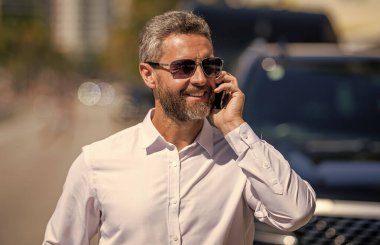 İş adamı dışarıda telefonla konuşuyor. Telefon kullanan bir iş adamı. İş görüşmesi. Erkek telefon konuşması. Telefonu olan olgun bir iş adamı. İş iletişimi. Müzakere çevrimiçi. Müşteri hizmetleri.