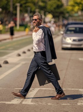 Takım elbiseli zengin iş adamı. İş portresi. Başarılı bir iş adamı dışarıda evrak çantasıyla dolaşıyor. İş adamı evrak çantasını tutar. İş adamı buluşmaya gidiyor. Şirket işi..