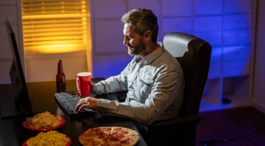 İş adamı geç saatlere kadar çevrimiçi içeriği izliyor. Freelancer geç saatlere kadar rahat bir şekilde çalışıyor. İspanyol 40 'lı yaşlarda dizüstü bilgisayar seyrediyor. Freelancer gece geç saatlerde pizza yer. İş adamı yorgun ve çok çalışıyor..