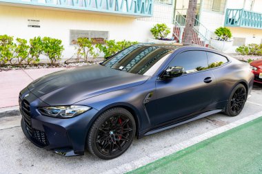Miami, Florida, ABD - 12 Temmuz 2025 Lüks BMW M4 Yarışması. Araba BMW M4 yarışması dışarıda park edilmiş. Siyah mat araç, köşe manzaralı. 2022 BMW M4 yarış arabası.