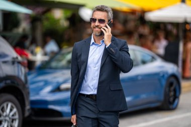 Zengin iş adamı dışarıda telefonla konuşuyor. Telefon kullanan bir iş adamı. Erkek telefon konuşması. Akıllı telefonlu İspanyol bir iş adamı. İş iletişimi. Adam yürürken telefona cevap verir..