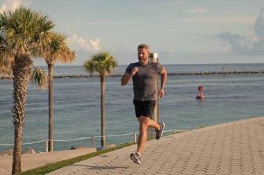 Kumsalda koşan adam. Spor yaşam tarzı. Yazın koşan sporcu. Spor koşuculuğu eğitimi. Sağlıklı yaşam tarzı ve günlük koşular. Koşan koşucu. Spor ve spor. Sabah koşusu.