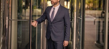 Ofis binasındaki İspanyol işadamı. Dışarıda başarılı bir iş adamı. Şehir caddesinde yürüyen bir adam. Takım elbiseli bir iş adamı. İş adamının iş başarısı. Takım elbiseli bir adam kırpık manzaralı ofise yürür..