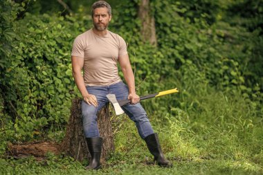 Ağaç kesen baltalı adam. Erkeksi vahşi adam. Oduncu dışarıda kamp yapıyor. Acımasız oduncu. Vahşilik ve erkeklik. Baltalı İspanyol oduncu adam. Oduncu baltası, bayrak.