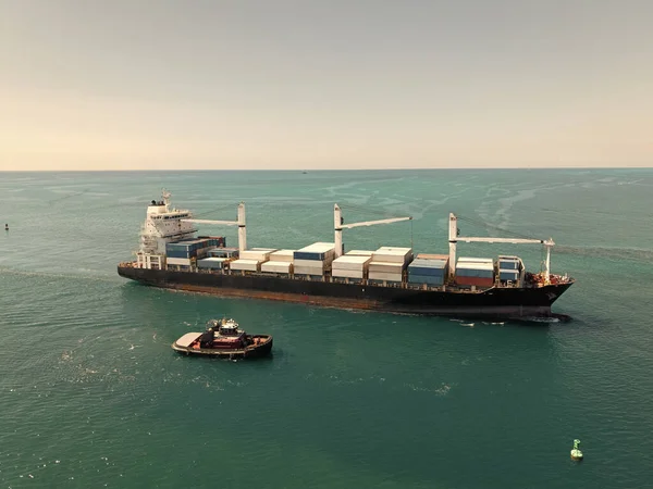 Yük konteynırı kargo gemisi ve römorkör. Kargo gemisi. Miami limanı. Monrovia konteynırı gemisi. Kargo Limanı Kaşif konteynır gemisi, deniz taşımacılığı.