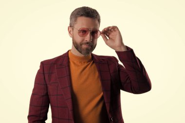 Moda erkek modeli şık bir ceket ve beyaz tenli güneş gözlüğü giyer..