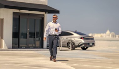 Şirket işi. Dışarıdaki telefonda iş adamı sohbeti. İş adamı telefonda sohbet ediyor. Akıllı telefon kullanan bir iş adamı. İnternette yakışıklı bir iş adamı sohbeti. İş adamı yürüyor. İş görüşmeleri.