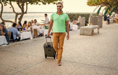 Gezgin yaz tatilinin tadını çıkar. Şehir caddesinde yürüyen İspanyol turist. Bavullu turist. 40 'lı yılların yolcusu. Yaz tatilindeki turist. Tatil gezisi için bavullar. Yaz turu.