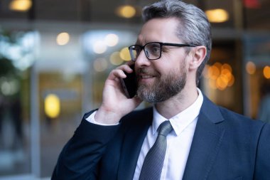 Ofisteki iş adamı. Takım elbiseli bir adam telefonda konuşuyor. Telefonu olan olgun bir İspanyol iş adamı. İş adamı iletişimi, kopyalama alanı. İş adamı portresi telefonda konuşuyor..