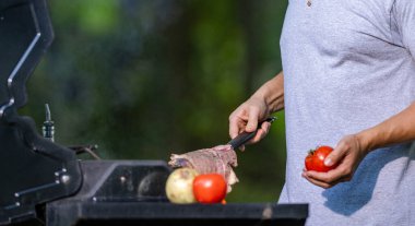 Adam dışarıda et pişiriyor. Arka bahçede domuz eti pişiriyorum. Man ızgara et barbeküsü. Barbekü ve ızgara. Kızartma ve ızgara yemek. Aşçı barbekü bifteği yapar. Izgarada et.