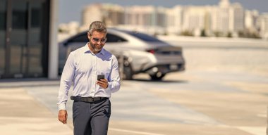 Dışarıdaki telefonda iş adamı sohbeti. İş adamı telefonda sohbet ediyor. Akıllı telefon kullanan bir iş adamı. İnternette yakışıklı bir iş adamı sohbeti. İş adamı yürüyor. Şirket işi. Boşluk afişini kopyala.