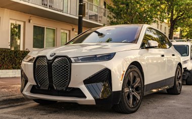 Miami, Florida, ABD - 05 Nisan 2025: BMW IX elektrikli SUV açık havada park edilmiş. Beyaz renkli araba, köşe manzaralı. 2025 BMW xDrive50 lüks elektrikli arazi aracı. Elektrikli geçiş aracı BMW IX xDrive50.