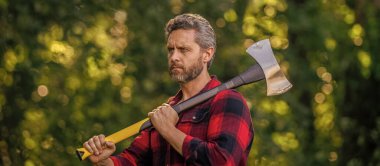 Ormanda baltalı oduncu adamlar. Oduncu baltayı taşır. Baltalı yakışıklı bir adam. Ormanda baltayla oduncu. Keresteci gömlekli ve baltası ağır. Güçlü adam ormanda çalışır. Odaklanmış ifade.