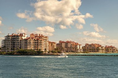 Marinaya yüzen bir tekne. Fisher Adası 'nda lüks bir yat teknesi. Yaz tatili. Fisher Adası konut binası ve lüks yat teknesi. Miami Fisher Adası Panorama Manzarası.