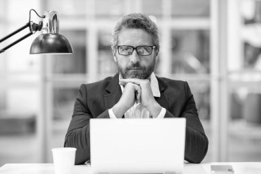 Çevrimiçi çalışan serbest çalışan. Ofiste dizüstü bilgisayar kullanan ciddi bir adam. Serbest iş yapma. Erkek ofis yöneticisi. İş adamının internet işi var. İş adamı başarısı. Serbest çalışan adam internette çalışıyor..