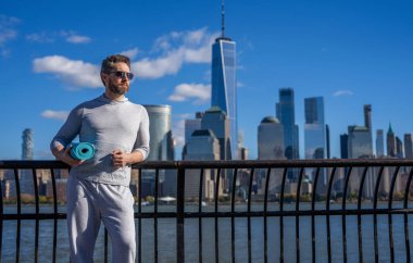Vücuduna uygun. Yoga reklamı. Sporcu adam antrenmana hazır. Sağlıklı bir yaşam tarzı. Spor ve spor. Eğitim için yoga minderi. New York 'ta sporcu. Manhattan 'da spor kıyafetli bir adam..