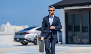 Başarılı bir anlaşmadan sonra takım elbiseli hırslı bir işadamı. Şirket işi. Zengin iş adamı kıyafeti. İş başarısı. Başarılı bir iş adamı evrak çantasıyla yürüyor. İş adamı çantası, kopyalama alanı.