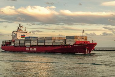 Miami, Florida, ABD - 3 Ocak 2025: Gündoğumunda konteyner gemisi. Kargo gemisi Seaboard Genesis ve konteynır Miami 'de. Yük konteynırı kargo gemisine yüklendi. Hava görüntülü kargo gemisi limana giriyor..