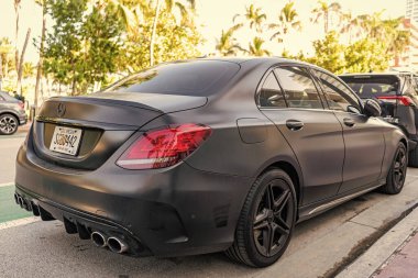 Miami, Florida, ABD - 07 Nisan 2025: Lüks siyah mat Mercedes Benz C W205. Mercedes Benz C W205 dışarıda park halinde. Siyah mat araba, köşe manzaralı. Mercedes Benz C W205 arabası.