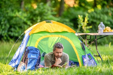 Sakin ol ve kamp alanında kitap oku. İlham zamanı. Kamp inzivasına çekilmiş. Yaz günü yürüyüş yapan bir adam. Yaz kampı ilhamı. Yaz kampı. Kamp macerası. Yürüyüş yaşam tarzı.