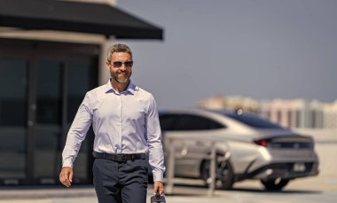 Açık havada başarılı bir iş adamı. Profesyonel iş adamı takım elbise giyer. İşadamı patron portresi. Başarılı bir iş. Başarı girişimci bayiliğinde. İş molasında ofis yöneticisi, afiş.