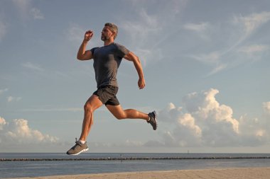 Spor ve spor. Kumsalda koşan adam. Spor yaşam tarzı. Yazın koşan sporcu. Aerobik yük. Spor koşuculuğu eğitimi. Sağlıklı yaşam tarzı ve günlük koşular. Koşan adam.