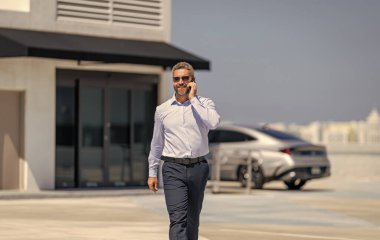 Müzakere çevrimiçi. İş adamı dışarıda telefonla konuşuyor. Telefon kullanan bir iş adamı. İş görüşmesi. Erkek telefon konuşması. Telefonu olan olgun bir adam. İş iletişimi. İş modeli.