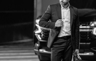 Takım elbiseli zengin iş adamı. İş portresi. Çantası park yerinde, manzarası kesik başarılı bir iş adamı. İş adamı evrak çantasını tutar. Takım elbiseli olgun iş adamı. Şirket işi. Boşluğu kopyala.