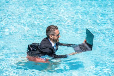 Yaz tatili. Komik çılgın iş adamı resmi olarak havuzda dinleniyor. Çılgın yaz gezisi. Eğlenceli iş hayatı. Yüzme havuzunda dizüstü bilgisayarı olan iş adamı..