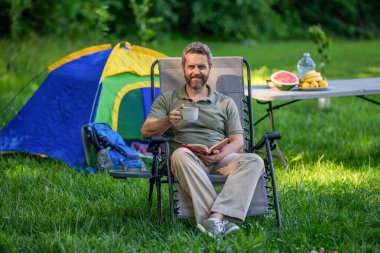 Kamp macerası. Doğada sabah kahvesi. Kamptaki adam sabah kahvesini içiyor. Yaz günü doğa yürüyüşçüsü. Yaz kampı ve doğa tatili. Adam yaz kampı. Hayatın tadını çıkarıyorum..